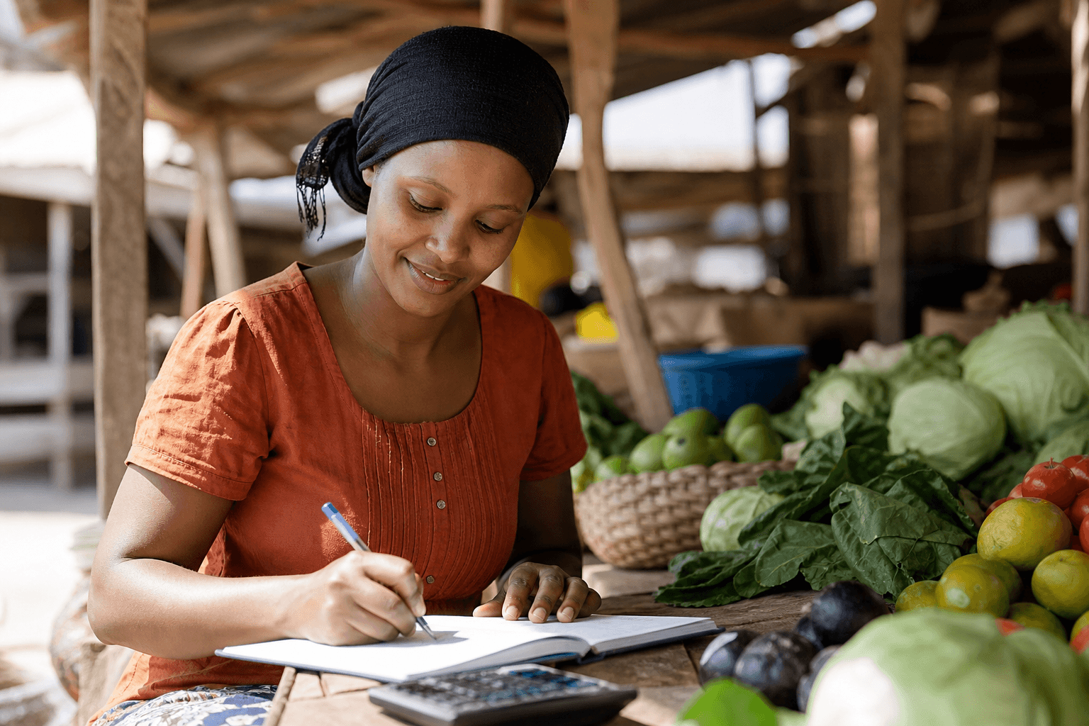 Market trader writing a budget in a notebook beside fresh produce